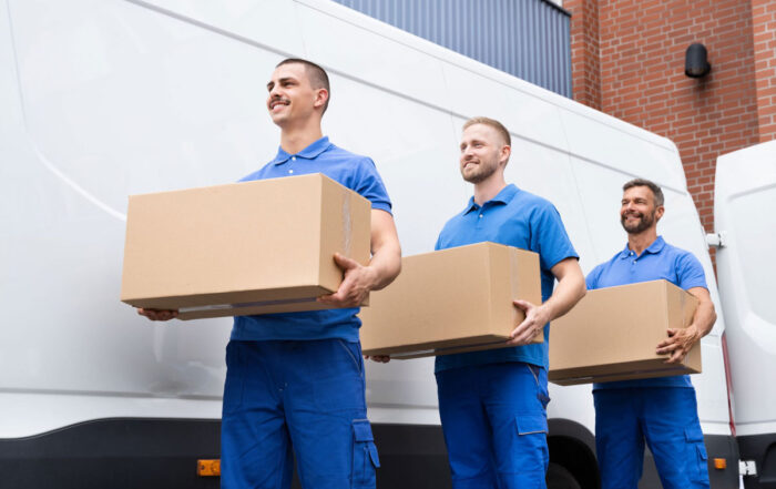 Three men in blue uniforms carrying boxes, representing professional movers in Adelaide.